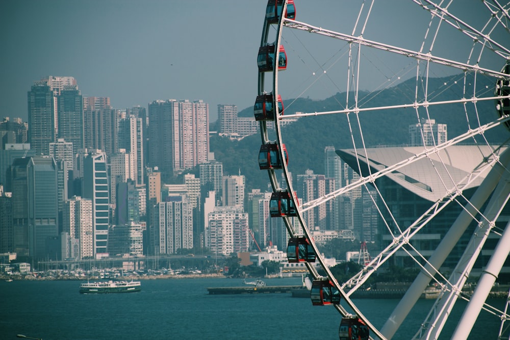 shallow focus photo of ferris wheel near body of water and city buildings