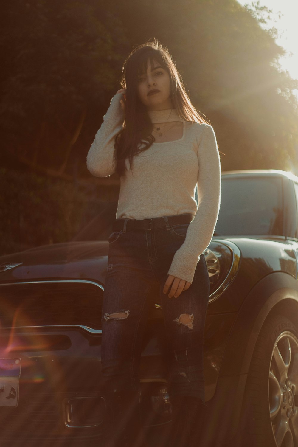woman wearing white long-sleeved shirt standing in front of black car