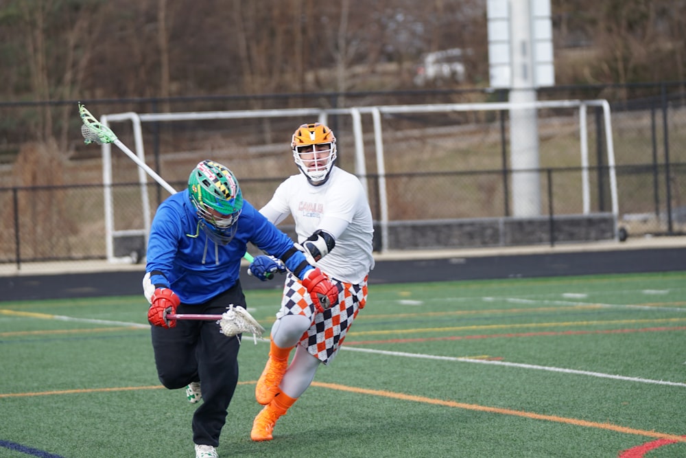 two men playing lacrosse game on field