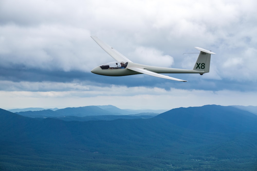avion X8 blanc au-dessus des montagnes pendant la journée