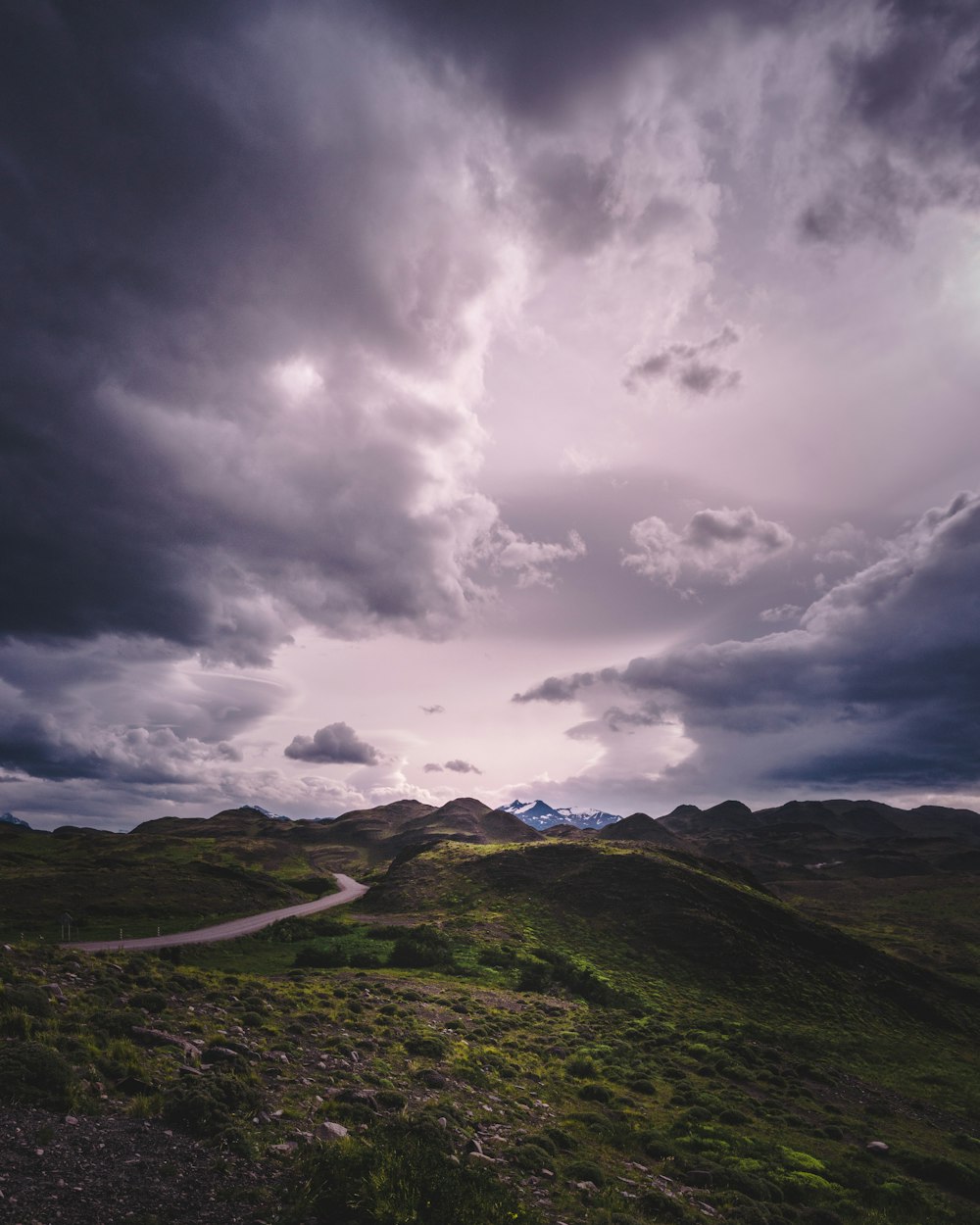 green mountain with road under gray cloudy sky