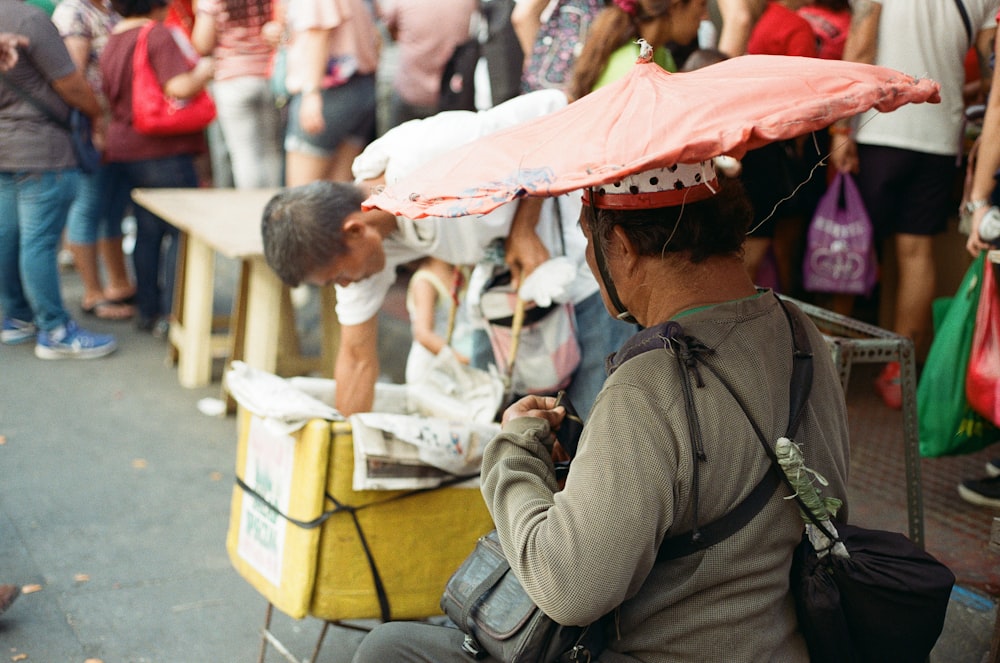 man leaning on box beside man sitting on chair near people standing on street during daytime