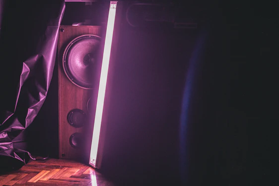 Close-up of a sleek Daf Acoustics speaker cone glowing under deep navy blue studio lighting with metallic reflections.