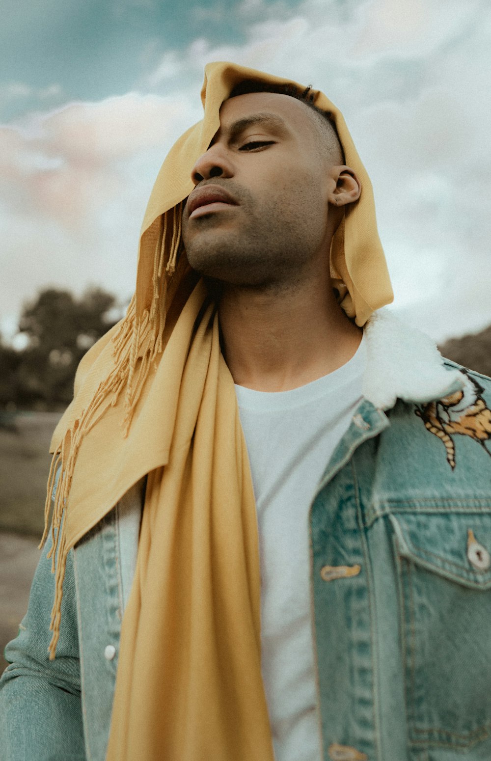 man covering his face with yellow scarf