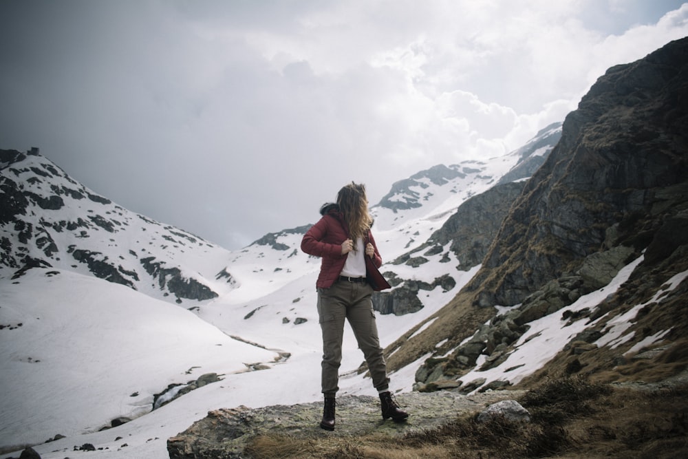woman standing on rock near mountain covered with snow