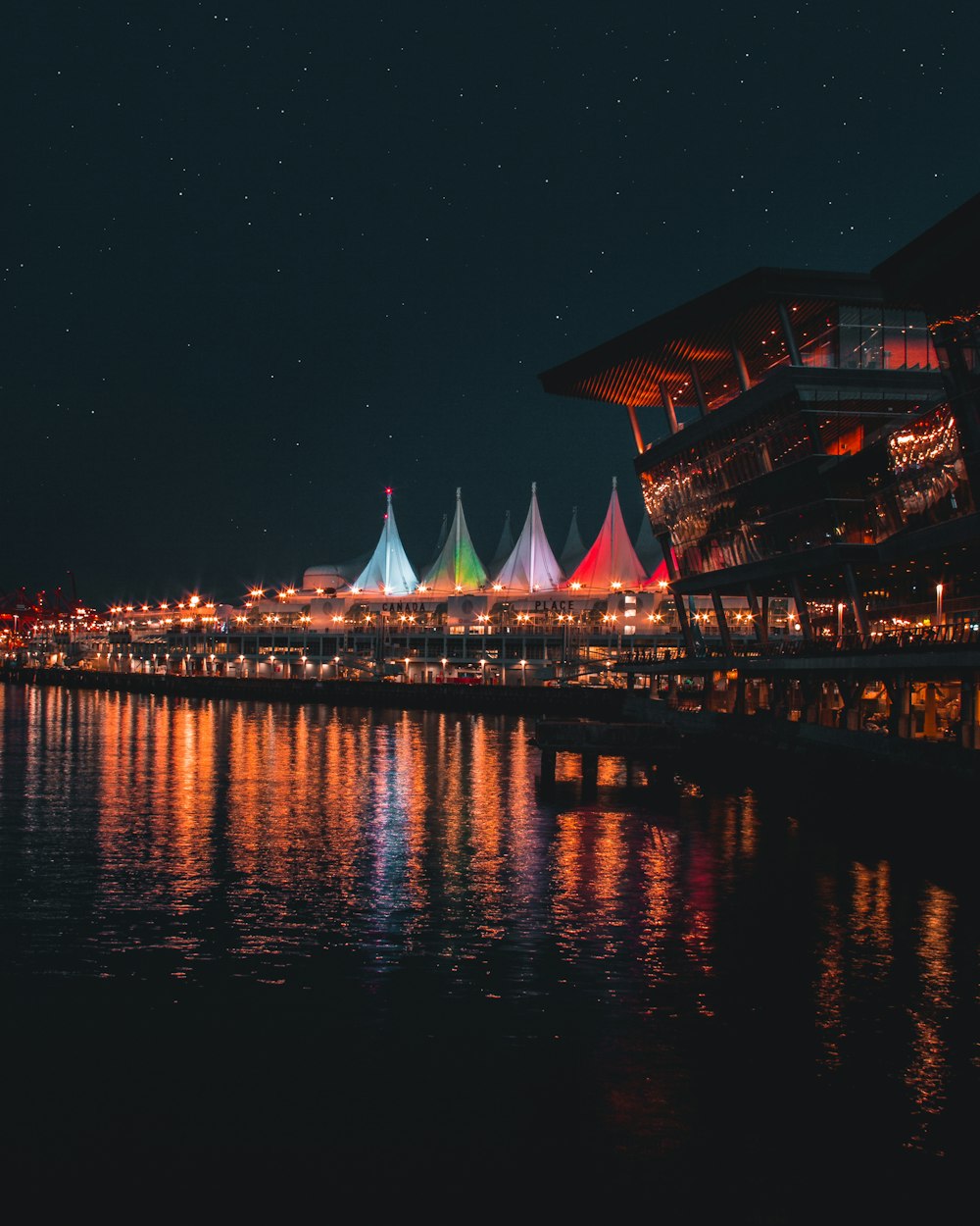 building near calm body of water during nightime