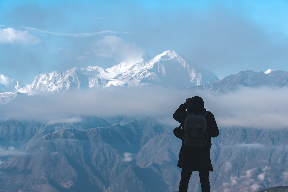 person wearing black jacket in front on mountain range