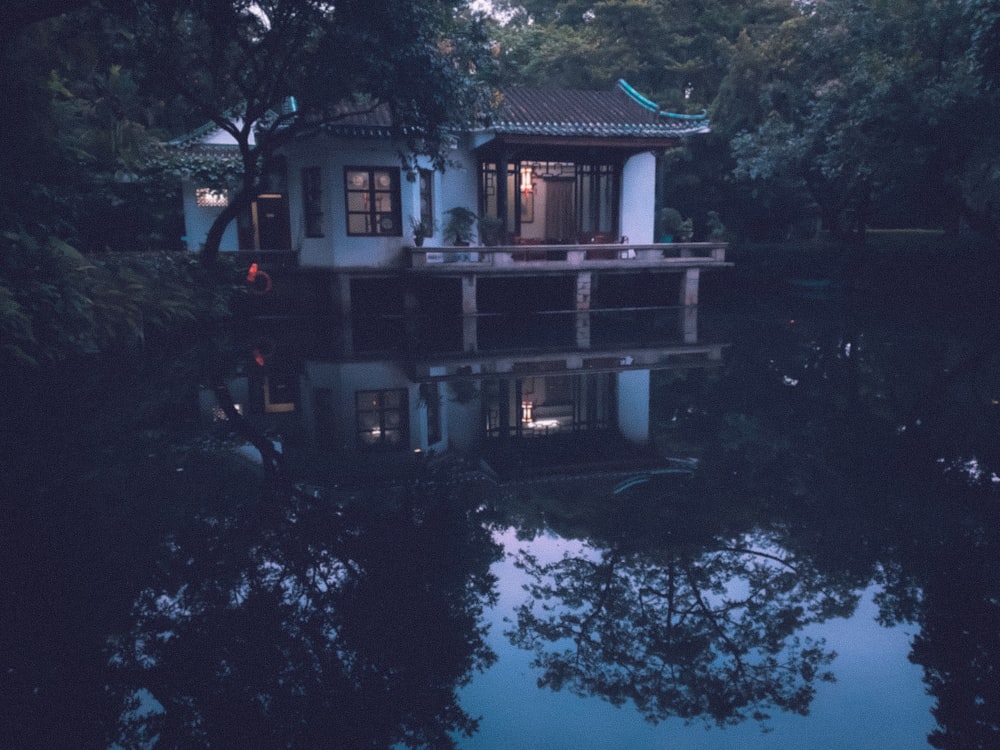 white wooden cabin above lake in forest