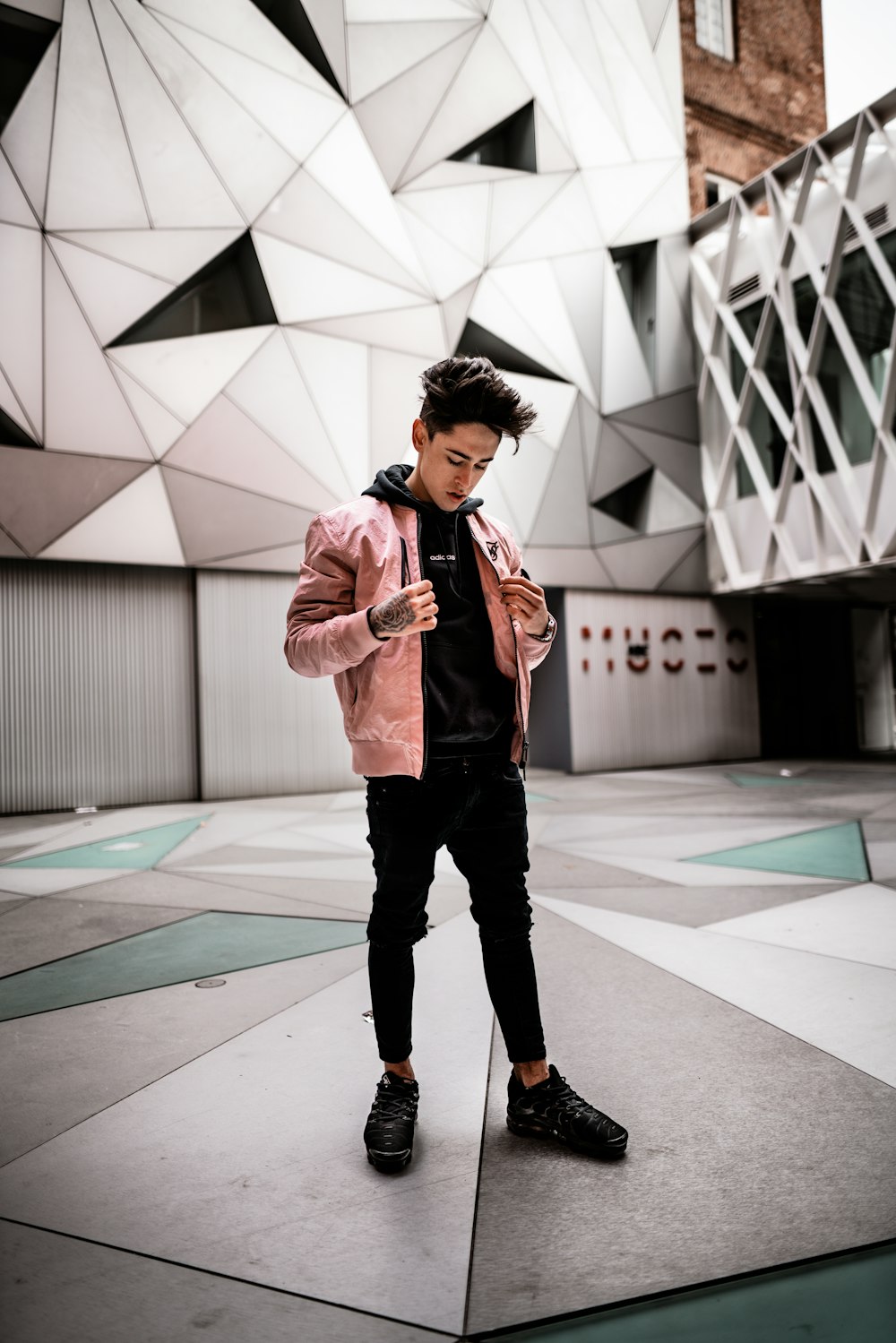 standing man wearing pink jacket looking down inside concrete building