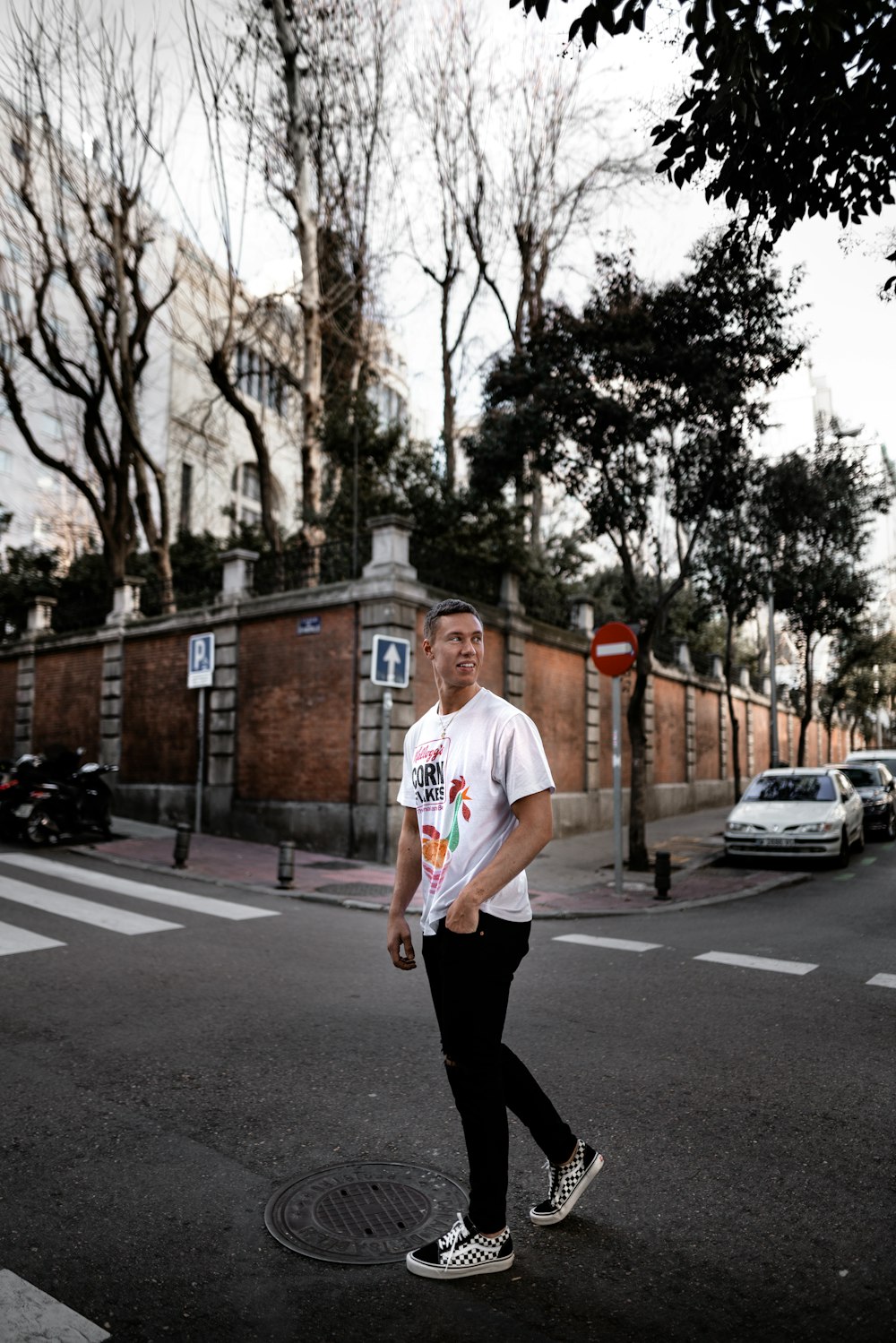 man standing at road under green tree