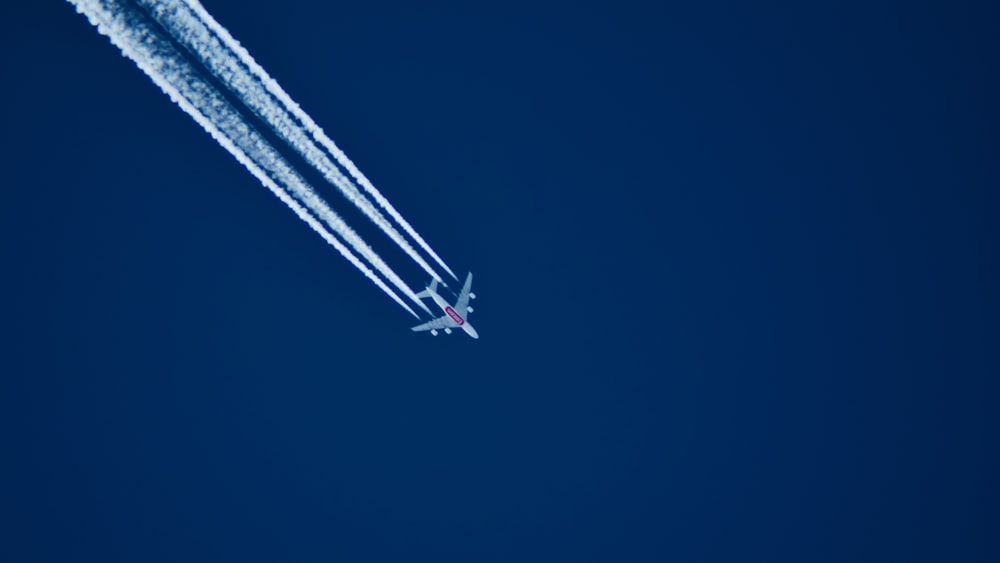 aerial photo of airplane with contrail during daytime