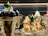 A display of two intricately prepared dessert glasses featuring soft serve ice cream. The dessert on the left includes dark chocolate pieces and is topped with mint leaves, while the dessert on the right is garnished with caramel sauce and almond slices, also adorned with mint leaves.