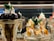 A display of two intricately prepared dessert glasses featuring soft serve ice cream. The dessert on the left includes dark chocolate pieces and is topped with mint leaves, while the dessert on the right is garnished with caramel sauce and almond slices, also adorned with mint leaves.