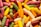 A vibrant assortment of elongated, cylindrical candies in various colors, including pink, yellow, green, white, and orange, scattered together creating a playful and colorful texture.
