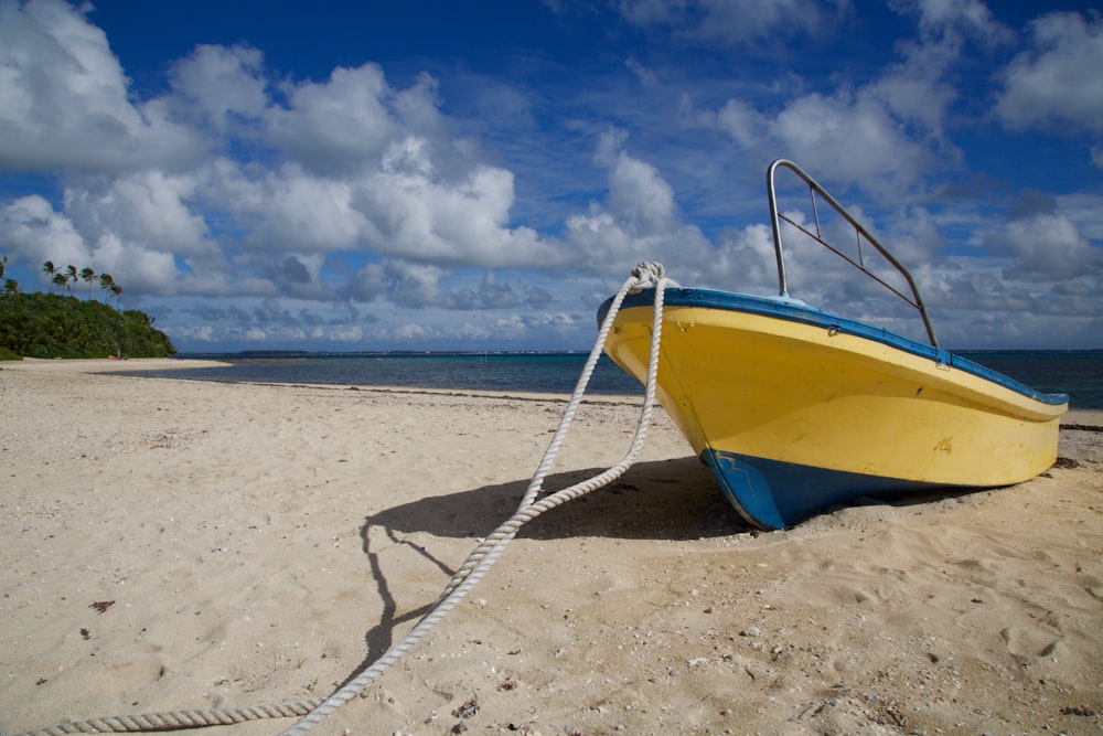 yellow and blue cuddy boat on seashore