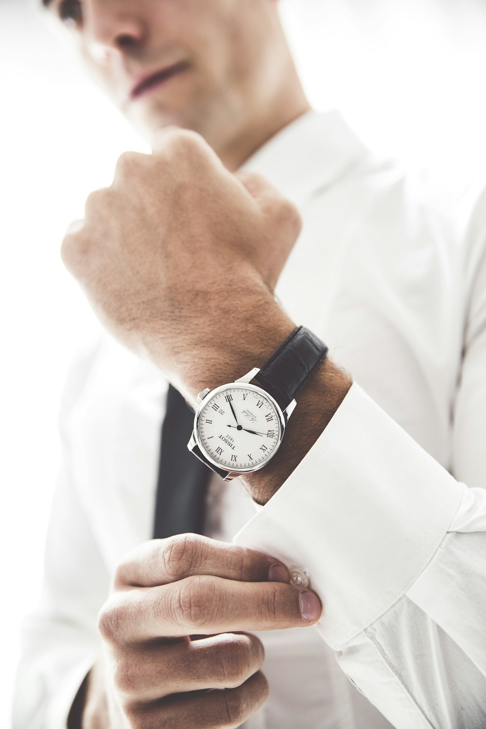 person wearing round silver-colored analog watch with black leather band