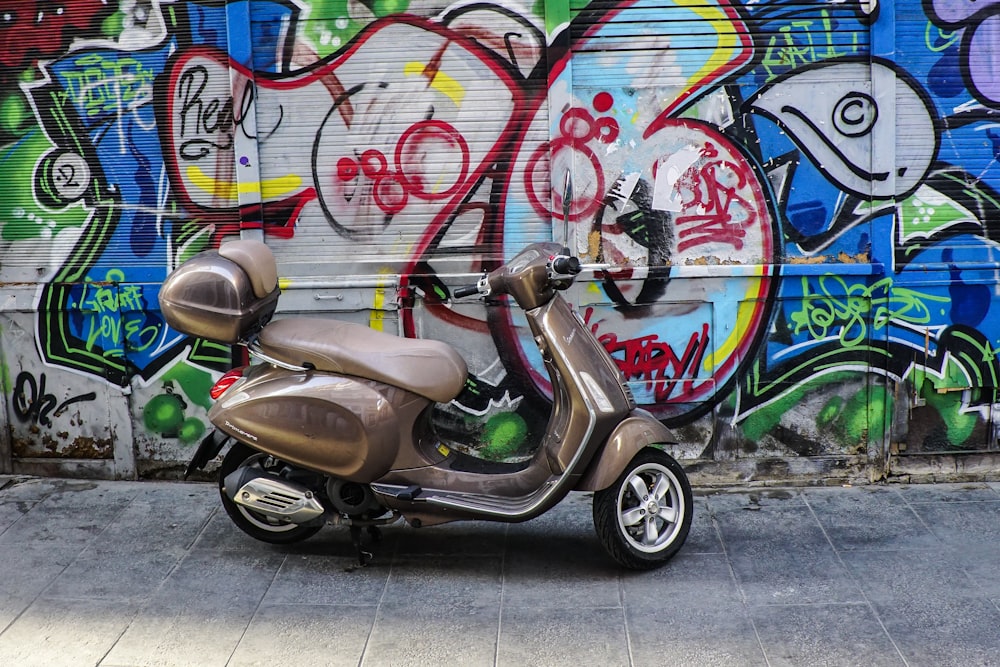 brown motor scooter parked beside graffiti wall