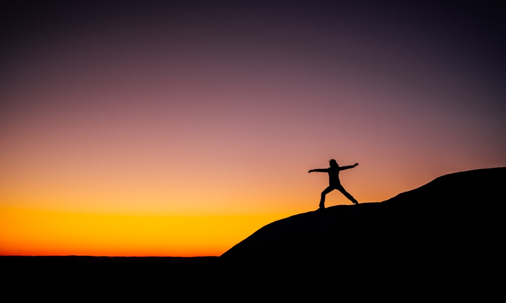 silhouette photo of person standing at the peak