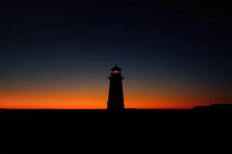 Minimalist lighthouse silhouette glowing softly against a dark blue background.