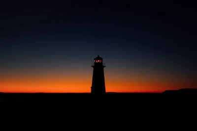 Minimalist lighthouse silhouette glowing softly against a twilight sky.
