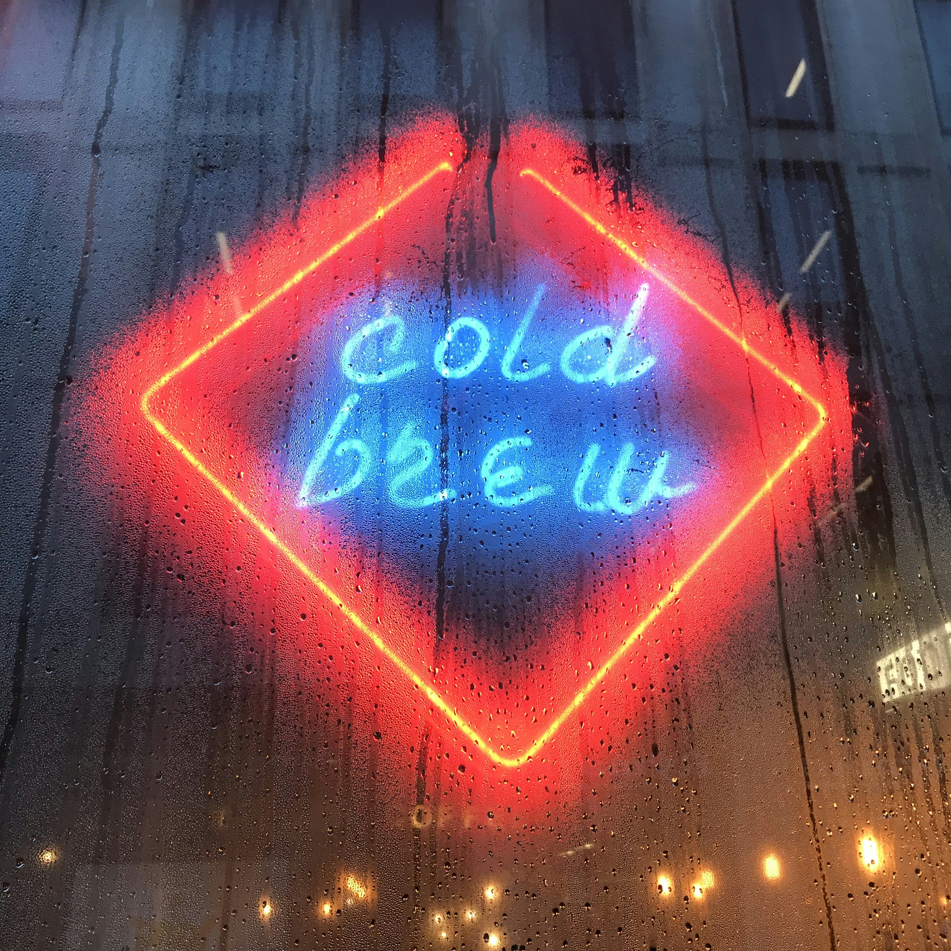 reflection of cold brew neon sign on glass wall
