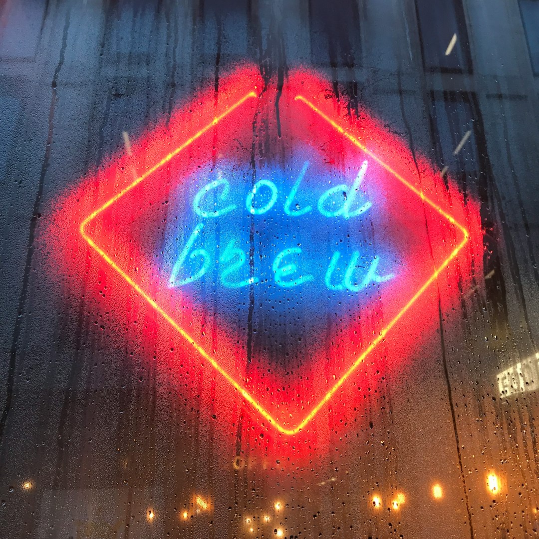 reflection of cold brew neon sign on glass wall