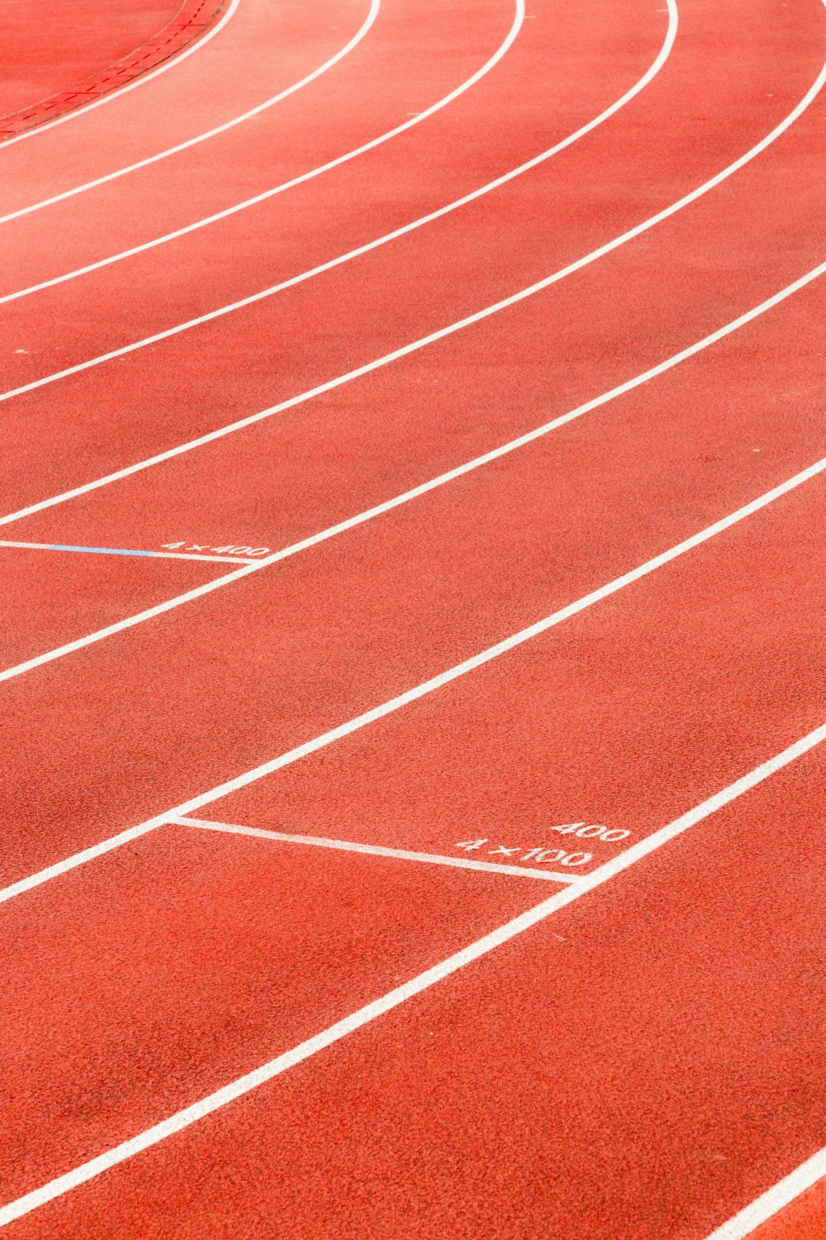 Curved lanes of a red running track marked for 400m and 4x100m, interval-training register