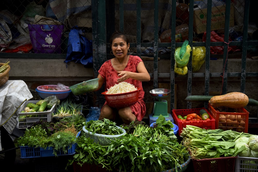 female vendor sits near weighing scale while selling vegetables