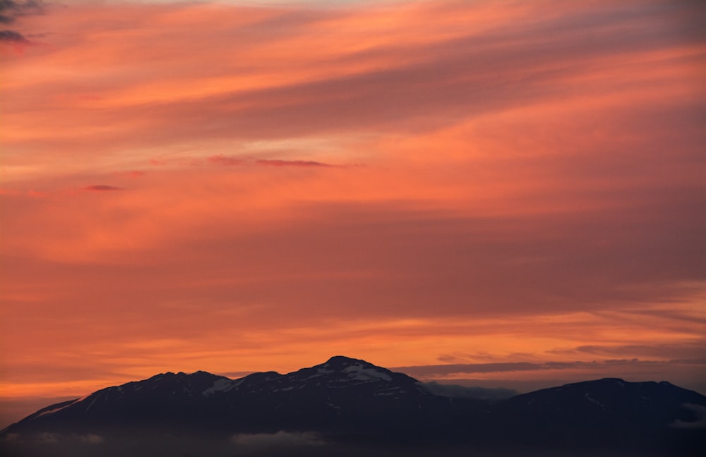 silhouette of mountains under cloudy sky