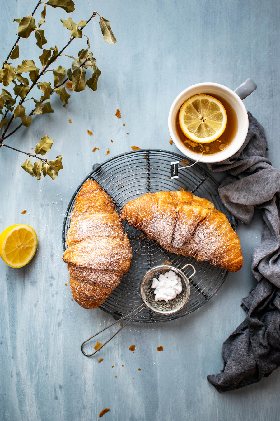 Croissants dusted with sugar on a round cooling rack