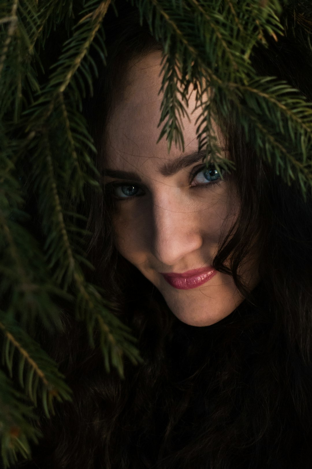 smirking woman hiding on green leaves