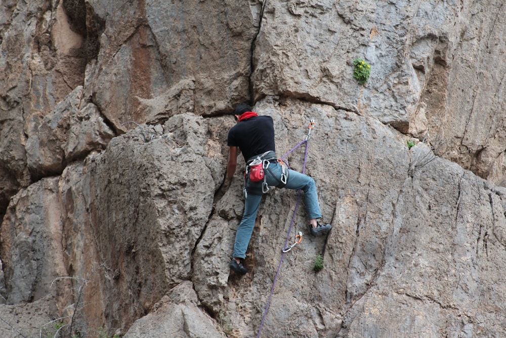 man climbing on gray rocky mountain during daytime