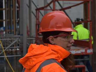 woman wearing red hard hat and orange reflectorized jacket