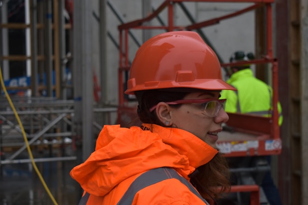 Close-up of a durable high-visibility construction jacket with reflective strips on a dusty worksite.
