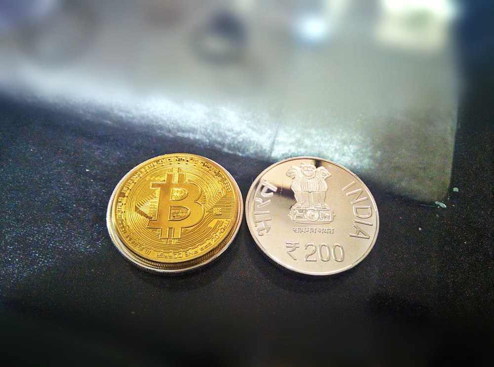 two gold-colored Bitcoin and 20 Indian rupee coin