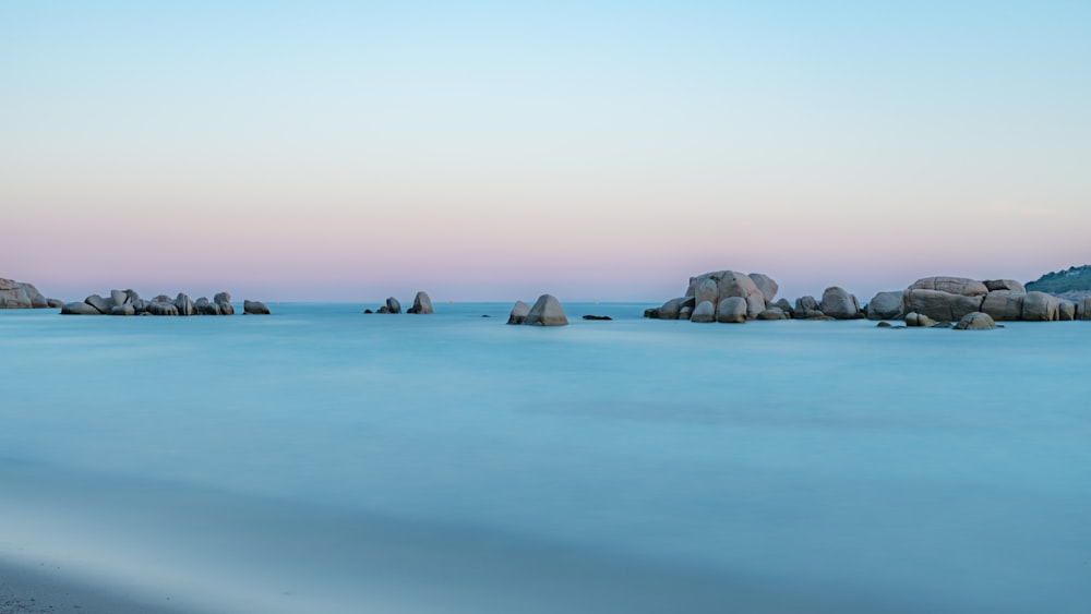 rock formation on calm body of water during daytime