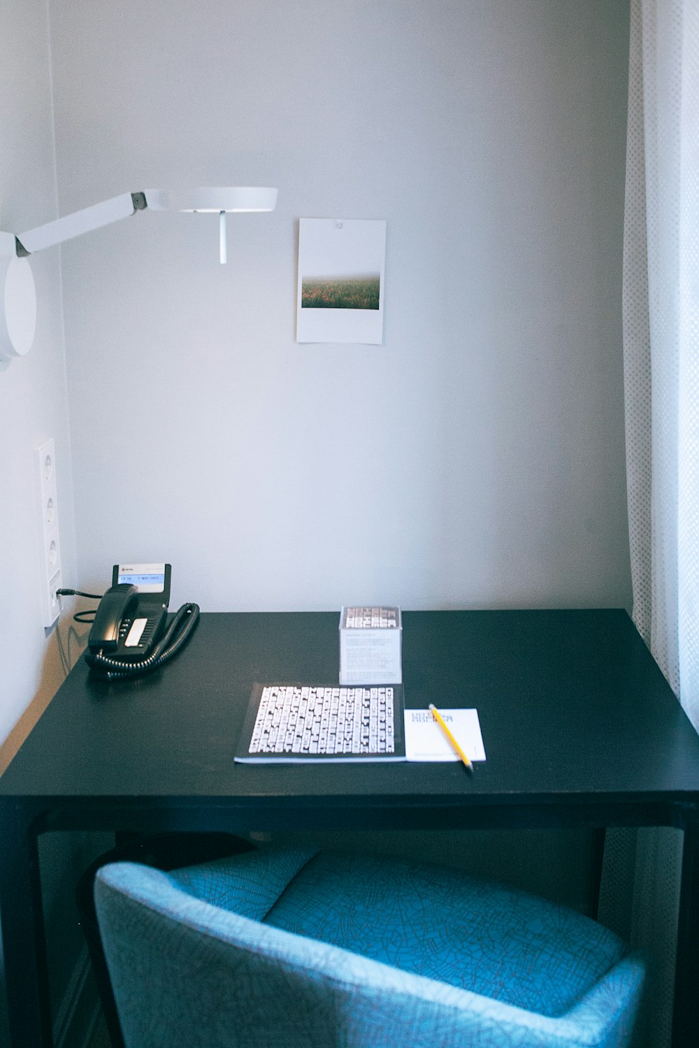 white and black book beside yellow pen and black telephone on rectangular black wooden table