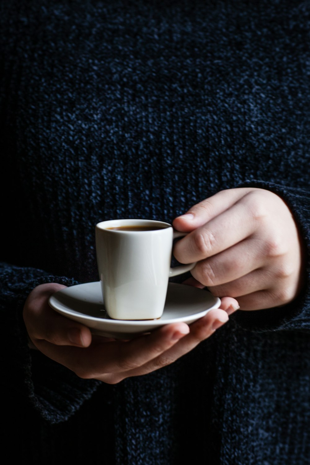 person holding cup of coffee on saucer