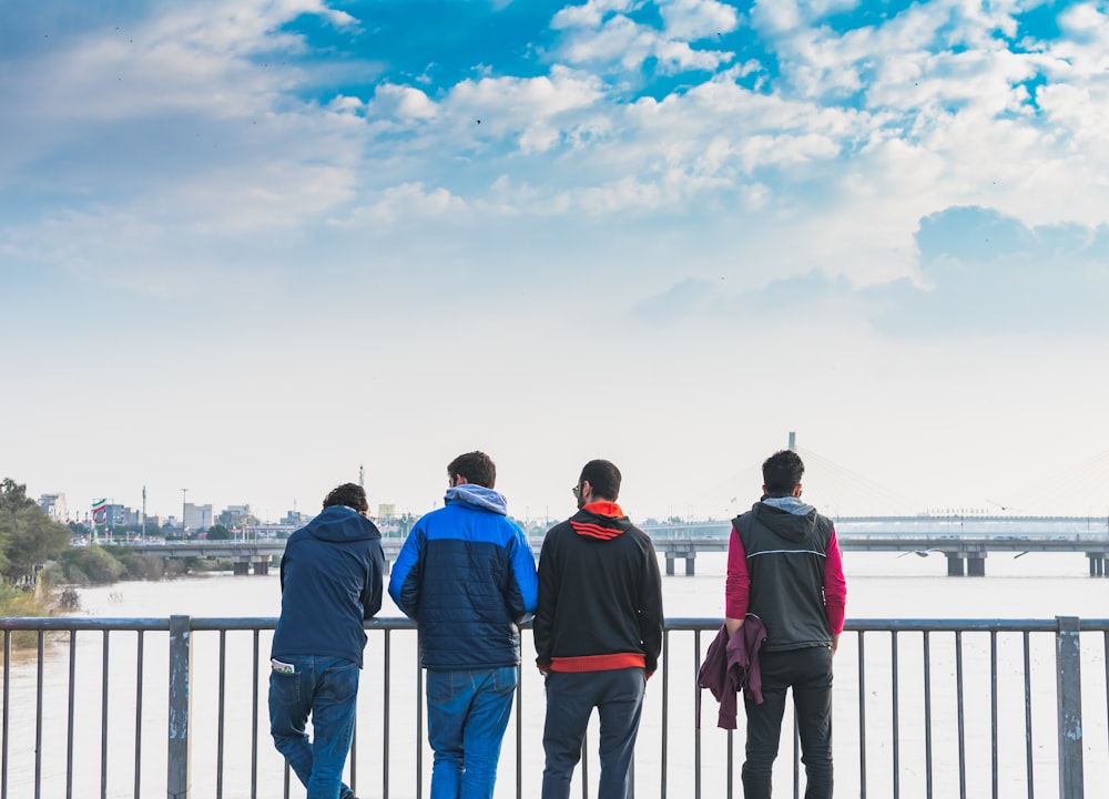 four man standing front on fence