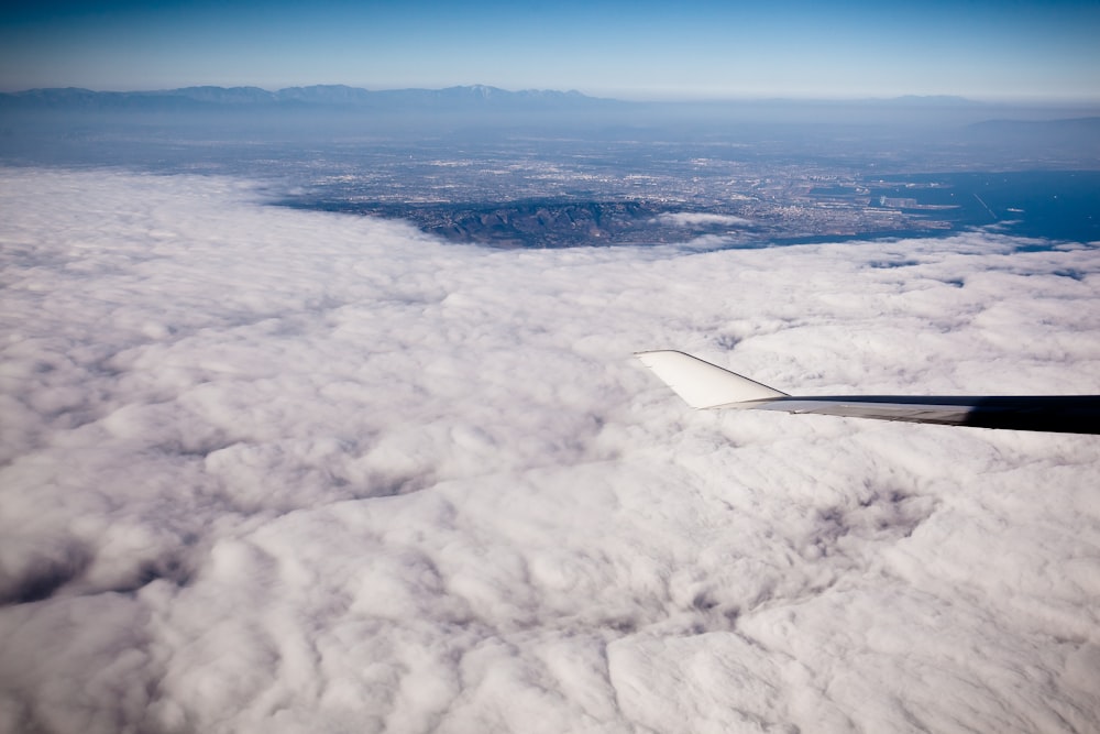 grey aircraft wingtip on flight above white clouds