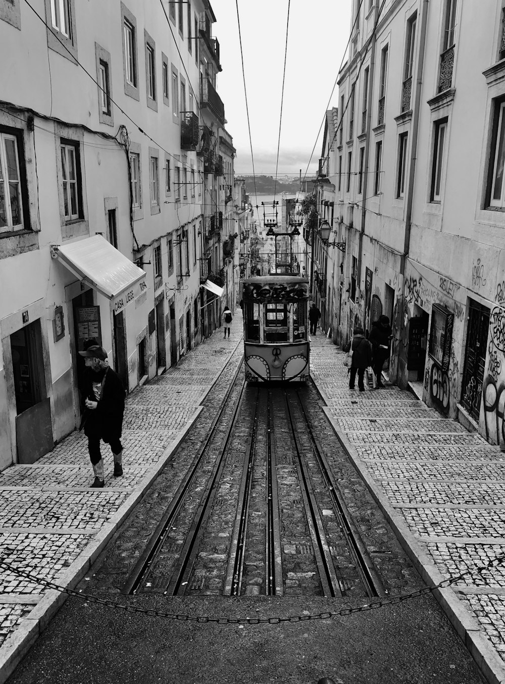 Fotografía en escala de grises de un tranvía que pasa por un callejón ascendente