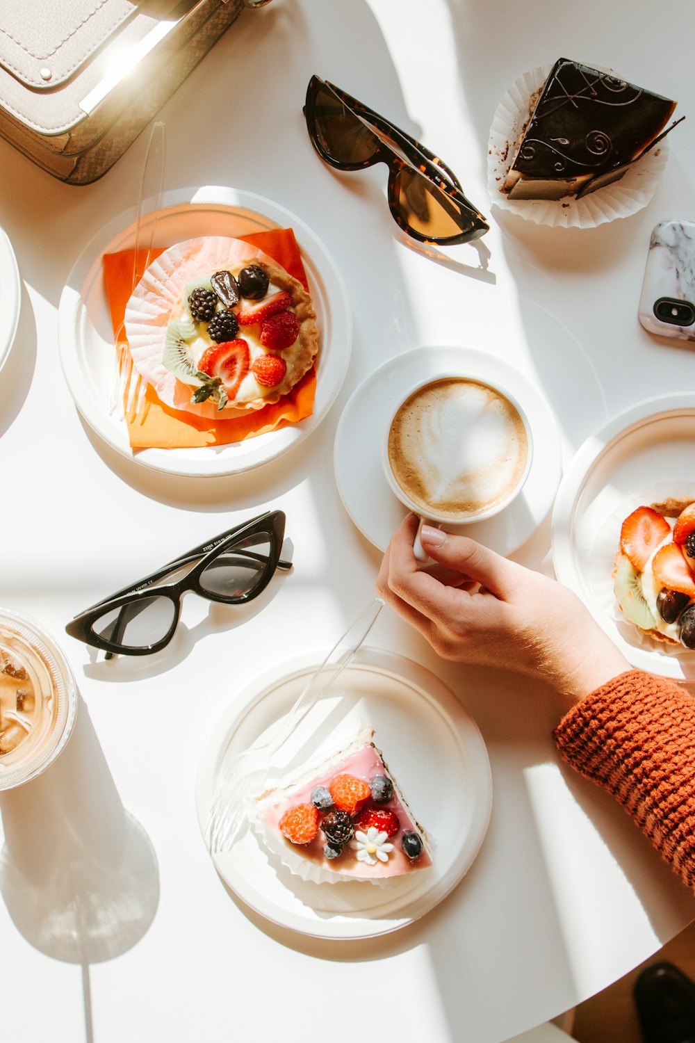 person reaching for filled ceramic mug between desserts