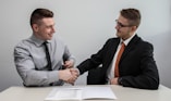 two men facing each other while shake hands and smiling