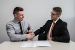 two men facing each other while shake hands and smiling