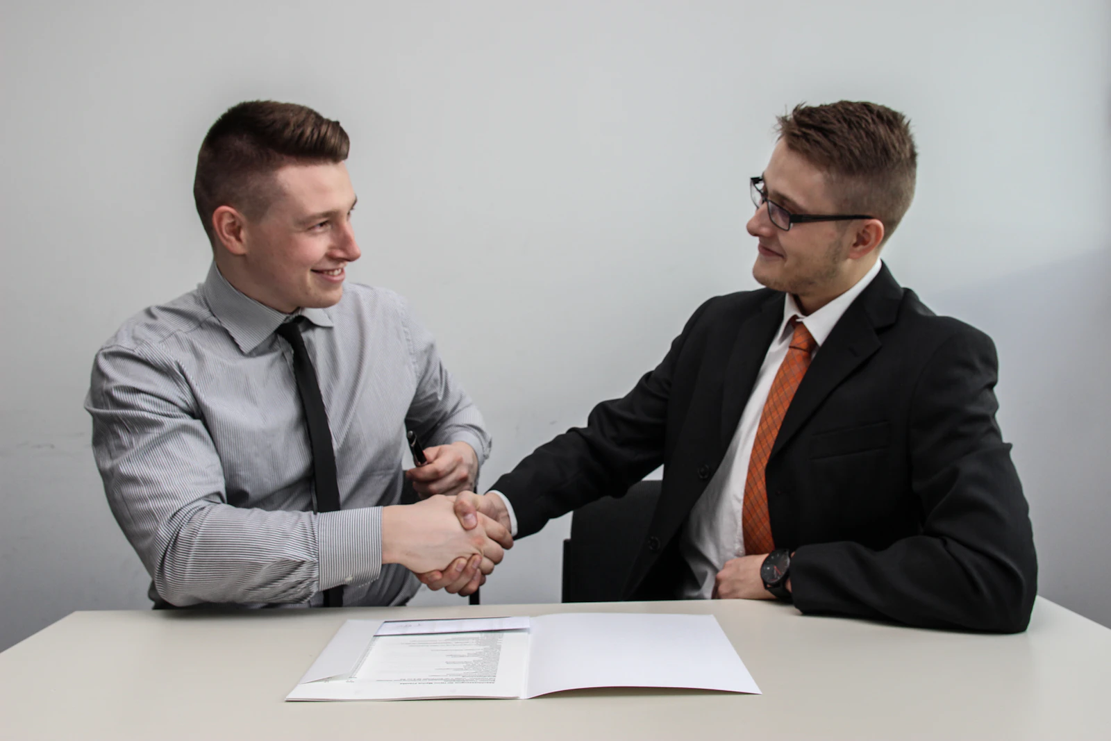 Dois profissionais apertando as mãos e sorrindo após uma entrevista