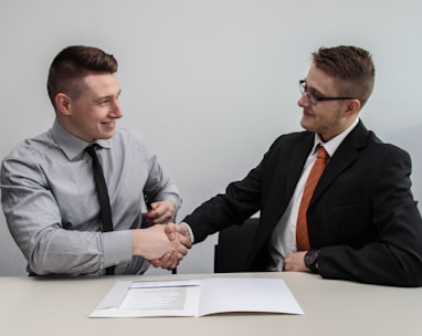 two men facing each other while shake hands and smiling