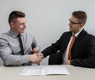 two men facing each other while shake hands and smiling