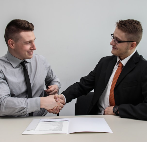 two men facing each other while shake hands and smiling