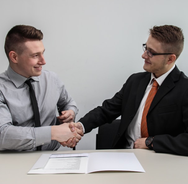 two men facing each other while shake hands and smiling