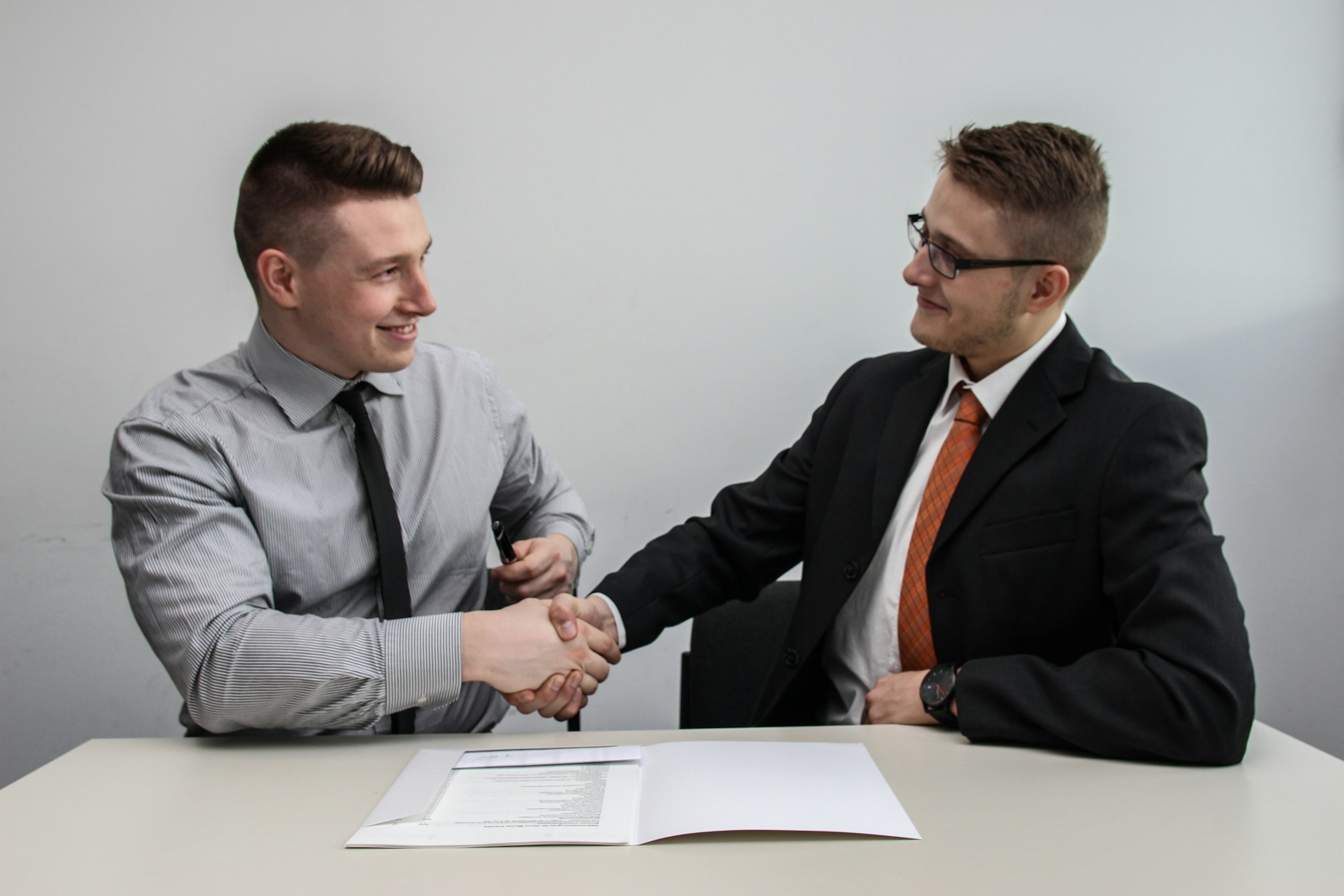 Two men shaking hands over a contract